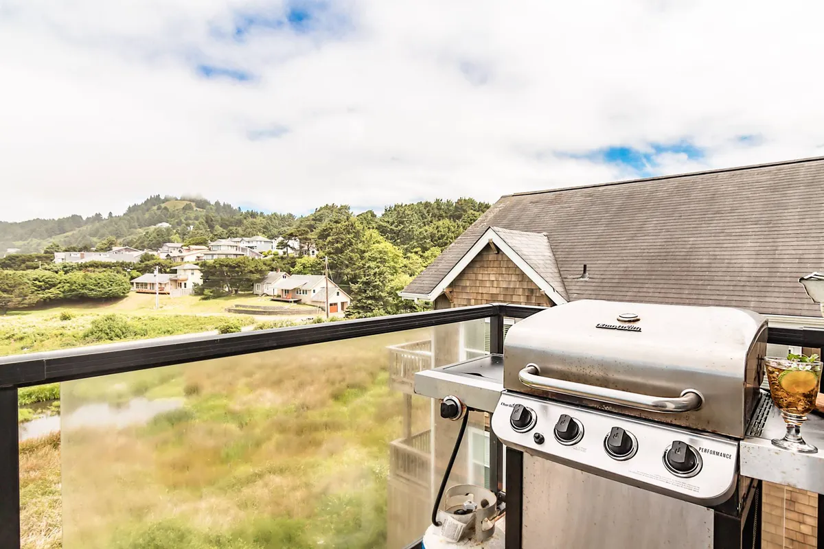 A relaxed balcony scene with a grill, a view of the surrounding landscape, and inviting space for barbecues and social gatherings. The sunset light and open air suggest moments of laughter and connection among friends and family.
