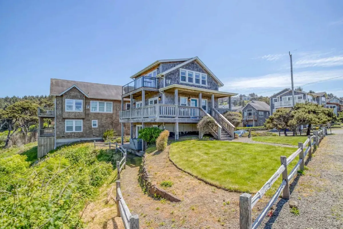 A cheerful exterior shot of the main house with a wraparound porch and a lush green lawn. The porch and lawn area suggest a welcoming environment for families and pets, with plenty of room to relax or play outdoors after a day of exploration.