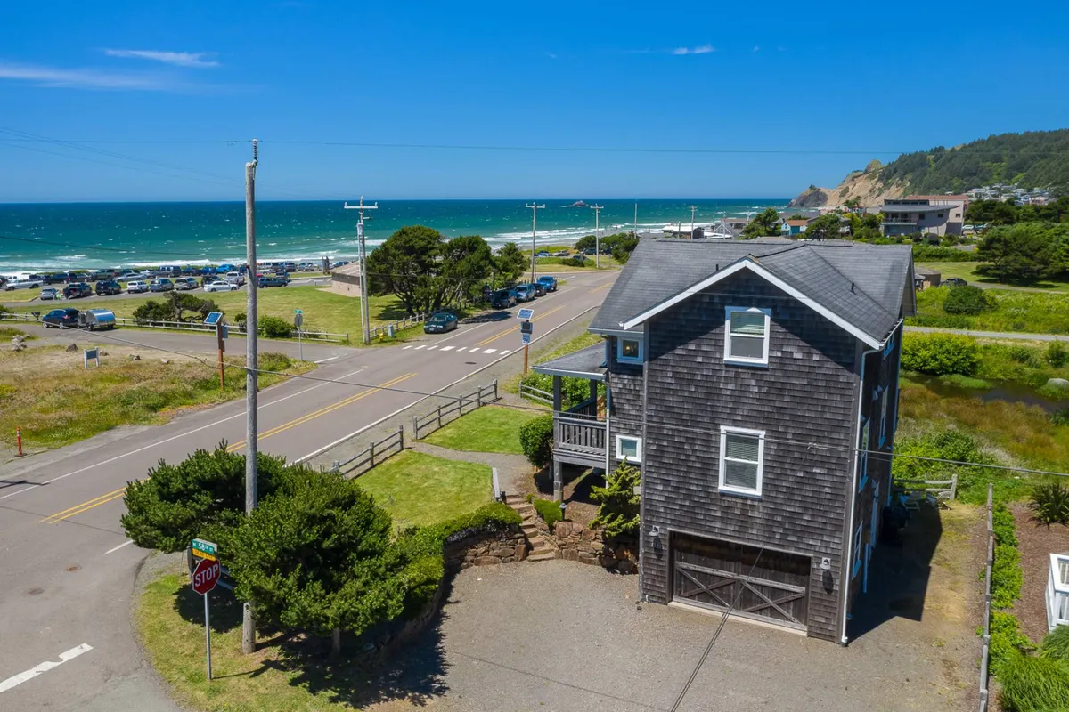 This image captures the house with the beach and the road just across, surrounded by lush greenery. The scene highlights the proximity to coastal trails, wetlands, and the beach, making it ideal for outdoor activities with pets. The home itself sits comfortably in a relaxed coastal environment.