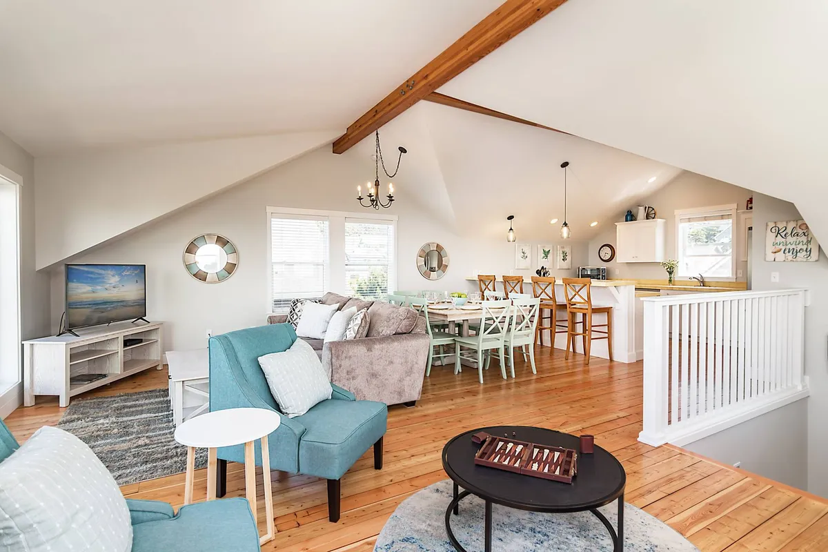 A warm, inviting interior with a turquoise armchair, a generous dining table, and stylish wooden beams. The space is set up for both casual dining and game nights, with seating that suggests togetherness and conversation.