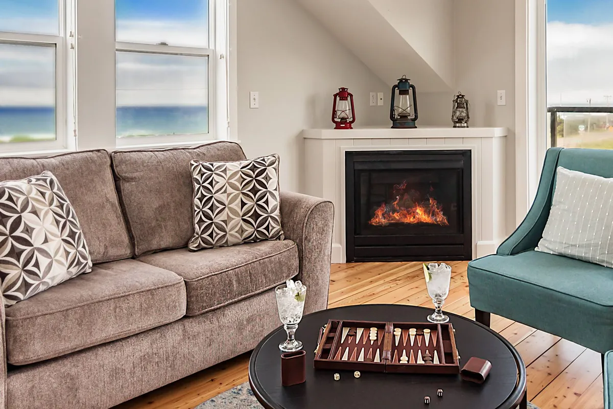 A comfortable seating area centered around a gas fireplace, with a coffee table set for a game of backgammon. Plush seating and playful decor suggest a space made for relaxation, laughter, and spirited board game competitions.