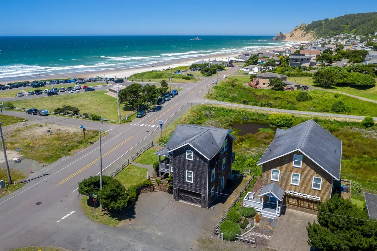 An inviting exterior view features beach access, ocean views, and surrounding greenery. The two houses and open space convey a sense of community and relaxation, while the easy access to open areas suggests plenty of space for pets to roam and play.